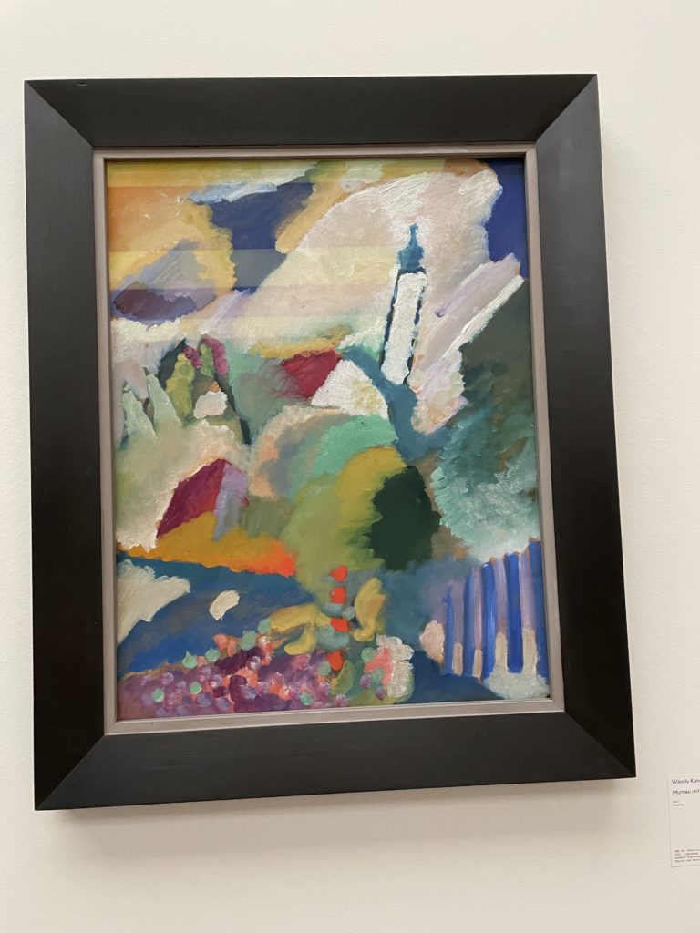 Bild von Wassily Kandinsky, mit Tupftechnik ist das Bild geschaffen. Eine Kirche ist erkennbar, dazu Berge.